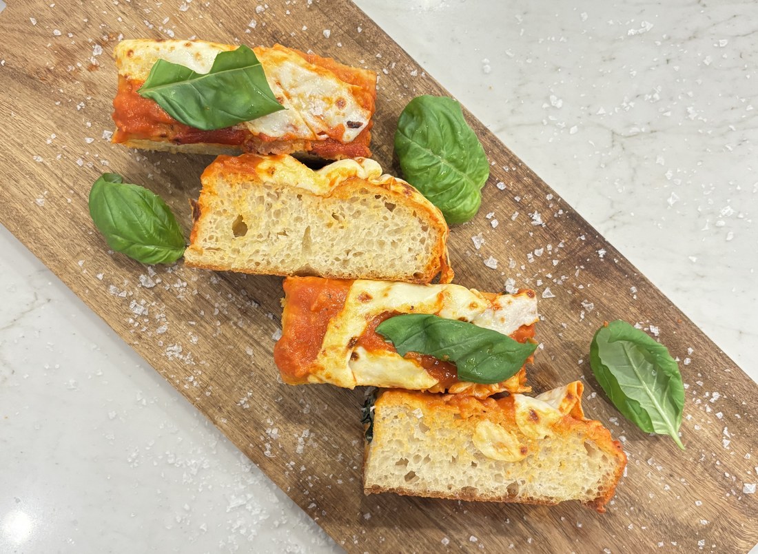 Sliced margherita focaccia with basil and melted mozzarella