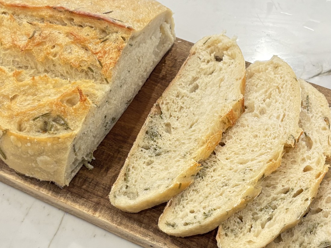 Sliced rosemary sourdough loaf on a wooden board