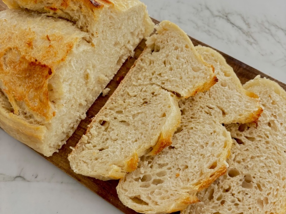 A sliced loaf of Crumb & Crust sourdough, showing an open, airy crumb